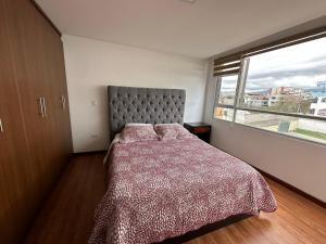 um quarto com uma cama e uma grande janela em Instant Hotel - Villa Palermo Luxury Apartments em Ambato