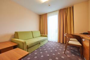 Šentjanž pri DravograduにあるHotel Korosicaの緑のソファとデスクが備わるホテルルームです。