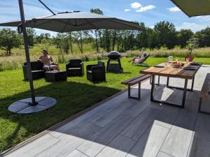 eine Terrasse mit einem Tisch, einem Sonnenschirm und einem Grill in der Unterkunft Gite les Caravottes 4 Etoiles avec Jacuzzi - JURA in Courlaoux