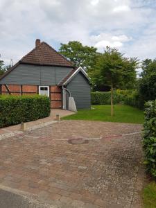 a house with a cobblestone driveway in front of it at Ferienwohnung Südheide in Beedenbostel