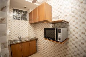 a kitchen with a microwave and a sink at Eden's Villa in Kumasi