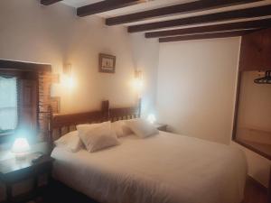 Schlafzimmer mit einem Bett mit weißer Bettwäsche und Kissen in der Unterkunft Viviendas rurales Fuente Domingo in Santillana del Mar