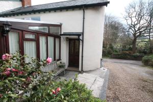 マインヘッドにあるForge Cottageの茶色の扉とピンクのバラが飾られた白い家