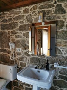 Baño de piedra con lavabo y espejo en Arrueiro, en Arrueiro