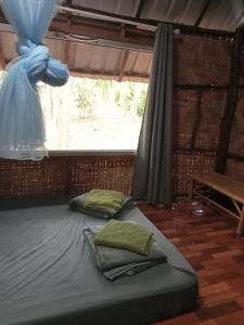 a bed with two pillows in a room with a window at Dahla Lanta Hut in Ko Lanta