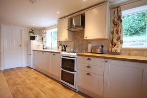 een keuken met witte kasten en een fornuis met oven bij Bridlecott, Monksilver 