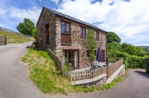 Casa de piedra con mesa y sombrilla azul en The Granary, en Luxborough