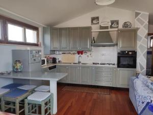 a kitchen with white cabinets and a counter with stools at Appartamento Silvana Terme in Rapolano Terme