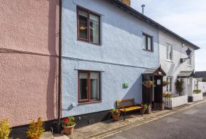 a blue building with a bench on a street at Cuain Cottage, Watchet in Watchet