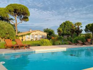 een zwembad met stoelen en een huis op de achtergrond bij LBCA maison campagnarde in Casteljaloux