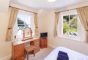 a bedroom with a desk and two windows at Lorna Doone Cottage, Lynmouth in Lynmouth