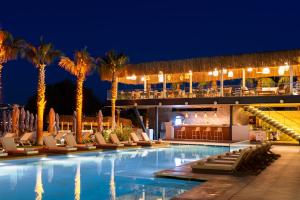 a hotel pool with chairs and palm trees at night at Arts Hotel Bodrum Yalikavak in Yalıkavak +60 photos
