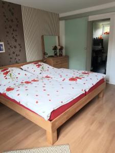 a bed with red flowers on it in a bedroom at Ferienwohnung Südheide in Beedenbostel