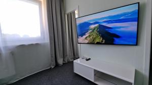 una TV a schermo piatto su una parete bianca in una camera di CityCenter Apartment - BigTV-PS4-Netflix-Parking a Chemnitz