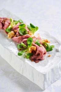 a plate of food with meat and greens on it at Hotel Korosica in Šentjanž pri Dravogradu