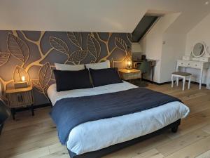 ein Schlafzimmer mit einem großen Bett und einer Wand mit Blättern in der Unterkunft Gite les Caravottes 4 Etoiles avec Jacuzzi - JURA in Courlaoux