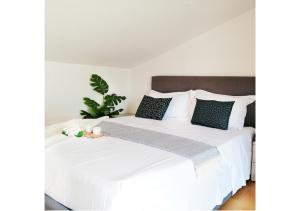 a bedroom with a white bed with black pillows at Holihome Gorycia House FRN in Alba Adriatica