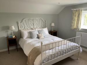 a bedroom with a white bed with two tables and two lamps at The Piggery, Dulverton in Dulverton