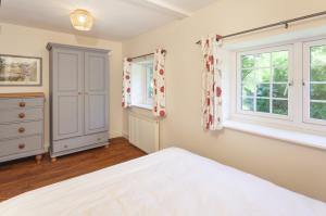 a bedroom with a bed and two windows at Jasmine Cottage Porlock in Porlock