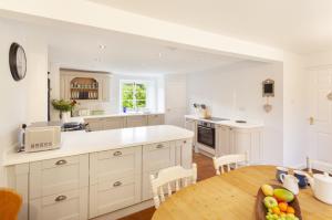 a kitchen with white cabinets and a wooden table at Trinity Cottage, Roadwater in Nettlecombe