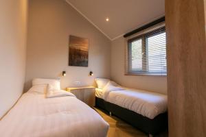 een slaapkamer met 2 bedden en een raam bij Pool Lodge - Vakantiepark de Thijmse Berg in Rhenen