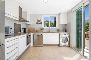 a kitchen with white cabinets and a washer and dryer at Villa Pepponi in Sant Lluis