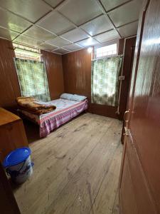 mały pokój z łóżkiem i drewnianą podłogą w obiekcie Odyssey Stays Siikhe Lake w mieście Hāpoli