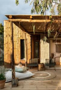 a wooden pergola with a bed and chairs on a deck at Ergon Beach House Nikiti in Nikiti