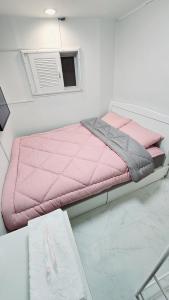 a pink bed in a white room with a table at Time Stay in Seoul