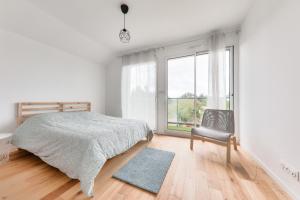 a bedroom with a bed and a chair and a window at Maison pour 8 - 300m de la plage du Rouvran in Le Tour-du-Parc