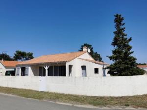 a white house with a fence and a tree at Maison de Vacances Rayons de soleil in Notre-Dame-de-Monts