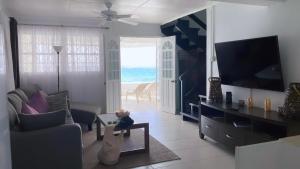 a living room with a couch and a television and the ocean at Purple Rain - Direct Beach Access, 2 Bedroom, 2 Terrace Holiday Home Bliss in Saint Peter