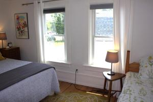 a bedroom with two windows and a bed and a chair at Maison Bloomfield in Bloomfield