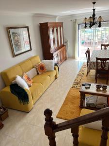 ein Wohnzimmer mit einem gelben Sofa und einem Tisch in der Unterkunft Villa Bela Vista near a surf spot in Ericeira