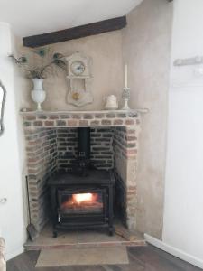 a brick fireplace with a stove and a clock at Gatekeepers Cottage Tiny House in Taizé +10 photos