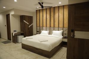 Mezkar Residency في Alwaye: غرفة نوم بسرير كبير مع اللوح الخشبي