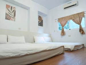 2 łóżka w białym pokoju z 2 oknami w obiekcie A-Lang Homestay w mieście Lanyu
