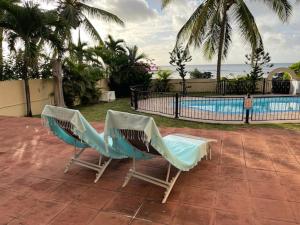 two chairs sitting in front of a swimming pool at Apartment with exceptional sea view in Trou aux Biches