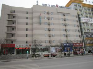 een groot wit gebouw op de hoek van een straat bij Jinjiang Inn Huainan Railway Station Middle Shungeng Road in Huainan