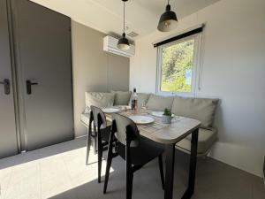 une salle à manger avec une table, des chaises et un canapé dans l'établissement Le Laurier, mobil-home climatisé avec vue sur mer, à Hyères