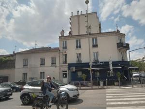 a man riding a bike in front of a building at Loft cosy et lumineux à Paris,Les Lilas dans un quartier convivial proche du métro 11 "Mairie des Lilas" et du tram T3b "porte des Lilas" in Bagnolet