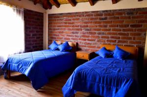 1 dormitorio con 2 camas y pared de ladrillo en Runa Wasi Quilotoa, en Quilotoa