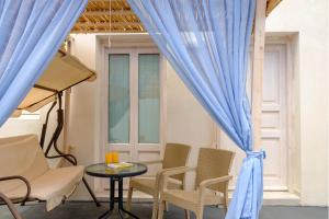 un patio con mesa y cortinas y sillas azules en Nalu Suites, en Fira