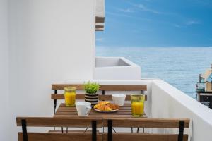 a table with a bowl of food and two glasses of orange juice at Makas Beach Suites Seafront Sea View in Hersonissos in Hersonissos