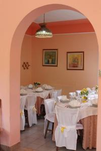 a dining room with white tables and white chairs at Agriturismo Menhir in Villagrande Strisaili