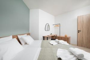 a white bedroom with two beds with towels on it at Makas Beach Suites in Hersonissos