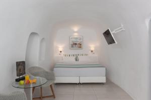 Dormitorio blanco con cama y mesa en Caldera Premium Villas, en Oia