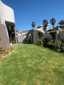 a yard of a house with green grass and palm trees at Imany Guest House in Bloubergstrand