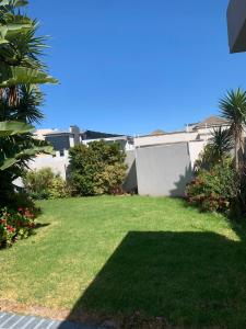 a yard with green grass and a white fence at Imany Guest House in Bloubergstrand