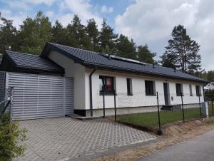 a white house with a black roof at Apartament Szum in Susiec